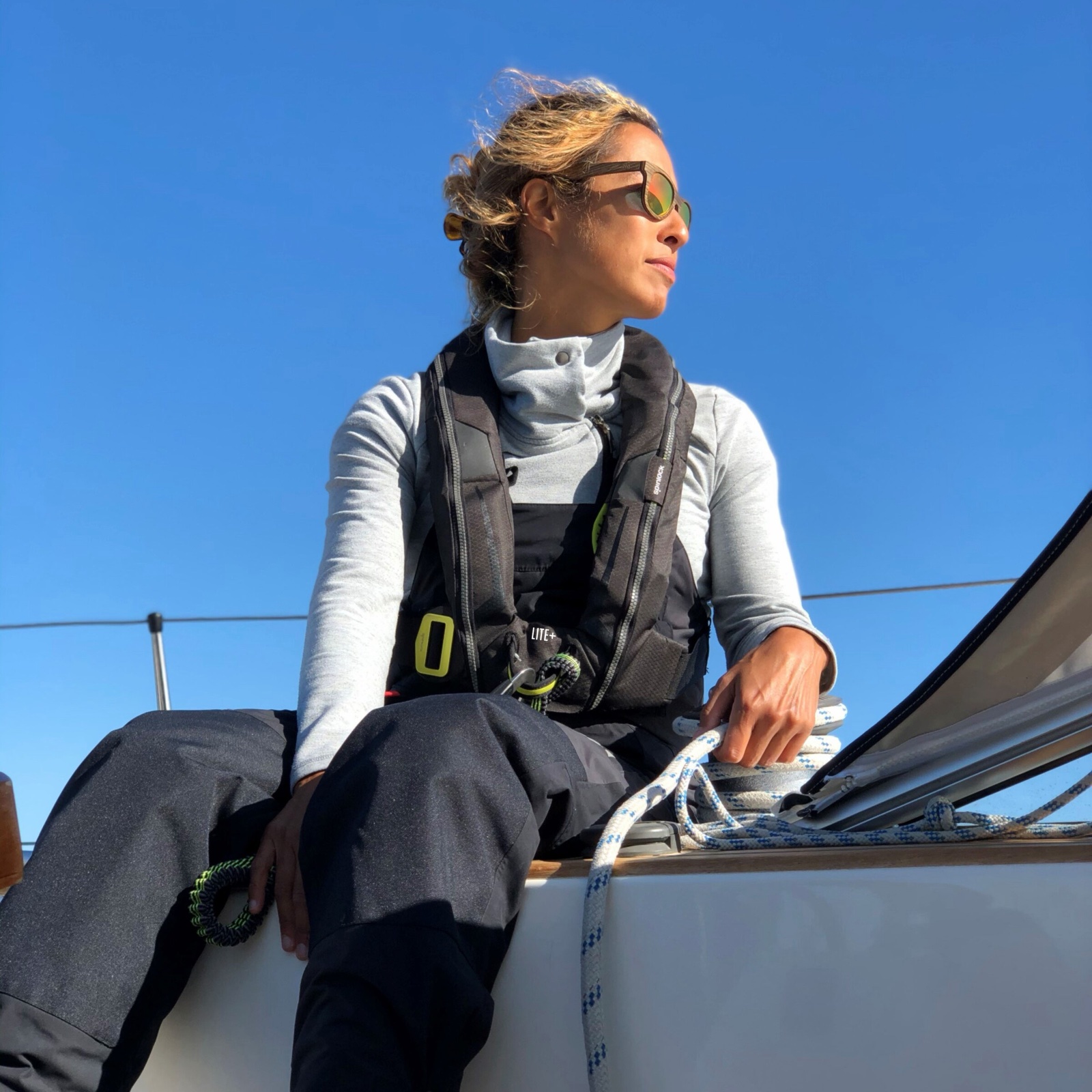 Jachtařka na palubě plachetnice v záchranné vestě s postrojem Spinlock Deckvest LITE+ a s připnutým jisticím lanem
